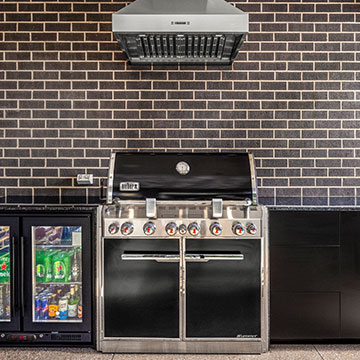 Front on view of BBQ with rangehood above, cabinets and fridge