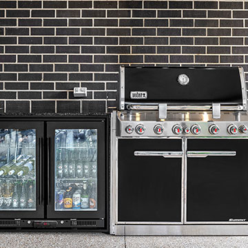Fridge and BBQ against black brick wall